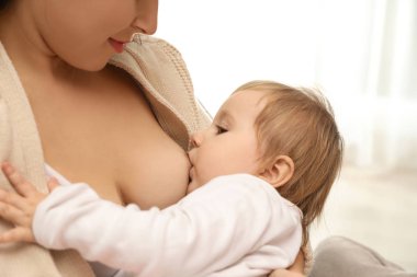 Kadın bebeğini evde emziriyor, yakın plan.