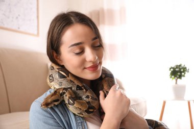 Evde boa yılanı olan genç bir kadın. Egzotik hayvan