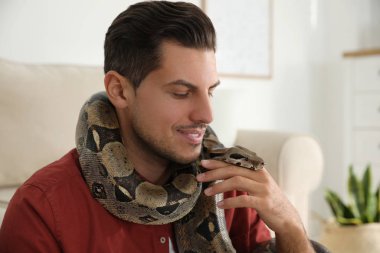 Evde boa yılanı olan bir adam. Egzotik hayvan