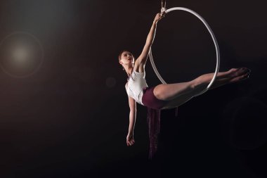 Genç bir kadın hava halkası üzerinde akrobatik bir element sergiliyor. 