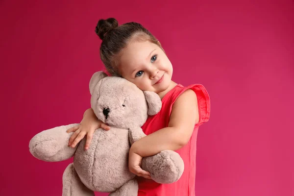 Niedliches kleines Mädchen mit Teddybär auf rosa Hintergrund — Stockfoto