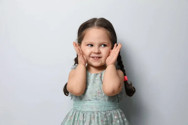 Schattig klein meisje op lichtgrijze achtergrond — Stockfoto