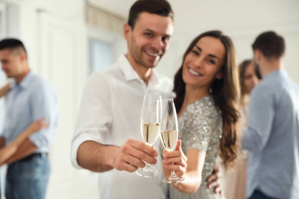 Lovely young couple with glasses of champagne at dancing party, 