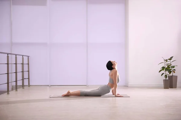 O tânără care practică cobra asana în studioul de yoga. Bhujangasana — Fotografie, imagine de stoc