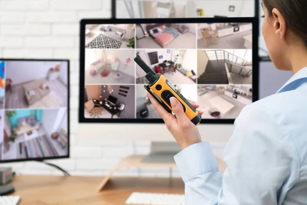 Female security guard with portable transmitter near monitors at workplace, closeup