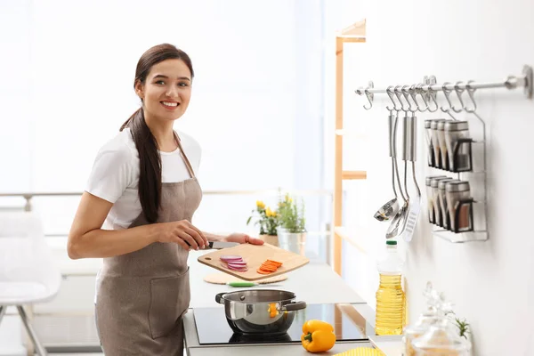 Fiatal nő főzés ízletes zöldségleves a konyhában — Stock Fotó