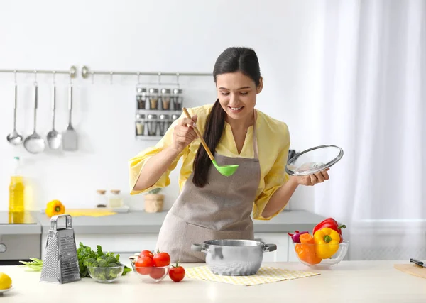 Giovane donna che cucina gustosa minestra in cucina — Foto Stock