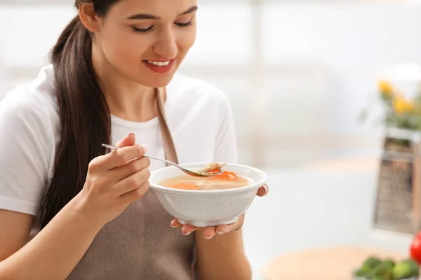 Young woman eating tasty vegetable soup indoors — Stock Photo, Image