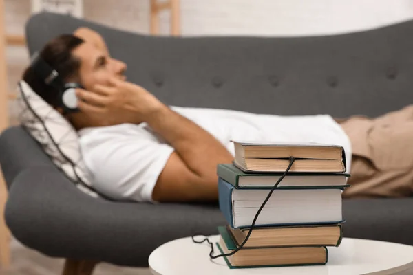 Mann mit Kopfhörer an Buch angeschlossen — Stockfoto