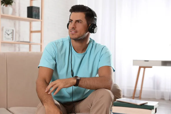 Muž poslouchající audioknihu doma na pohovce — Stock fotografie