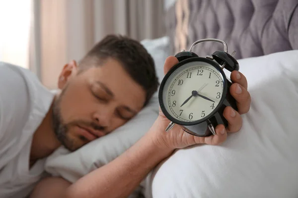 Mann mit Wecker schläft morgens zu Hause, konzentriert sich auf die Hand — Stockfoto
