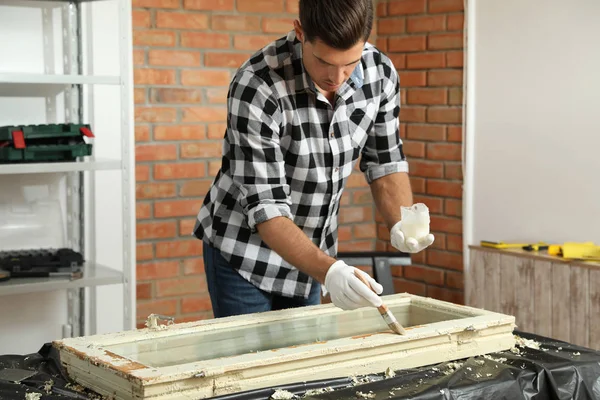 Man repareert oude beschadigde raam aan tafel binnen — Stockfoto