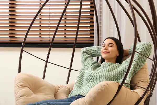 Junge Frau entspannt sich in Hängesessel am Fenster zu Hause — Stockfoto