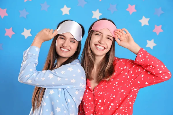 Hermosas mujeres con máscaras para dormir sobre fondo azul claro . — Foto de Stock