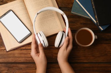 Kulaklıkları ahşap masanın üzerinde tutan bir kadın.