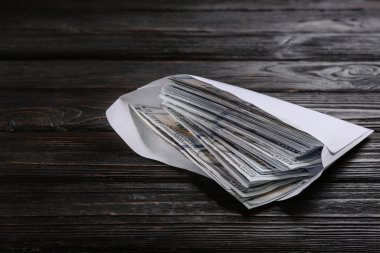 Siyah ahşap masanın üzerinde dolar banknotları olan zarf. Rüşvet kavramı