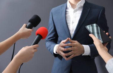 Profesyonel gazeteciler gri arka planda iş adamıyla röportaj yapıyor.