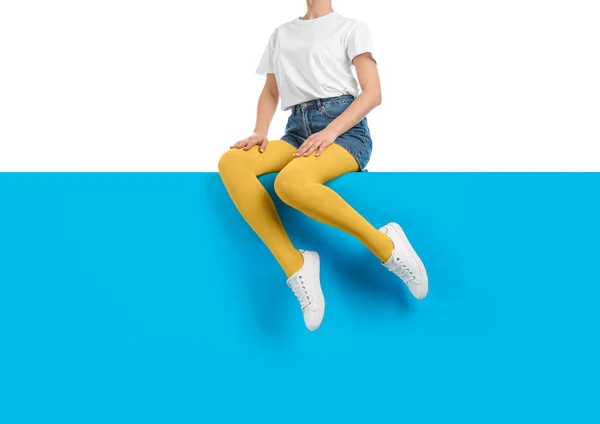 Mulher vestindo calças amarelas e sapatos elegantes sentado na cor b — Fotografia de Stock