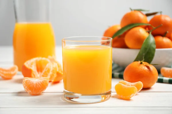 Glas frischen Mandarinensaft und Früchte auf weißem Holztisch — Stockfoto