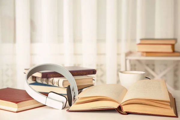 Livro aberto e fones de ouvido na mesa de madeira branca — Fotografia de Stock