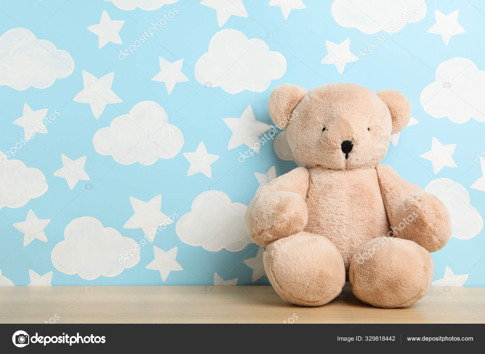 Teddy bear on wooden table near wall with painted blue sky, spac