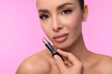 Pembe arka planda mat rujlu güzel bir kadın.