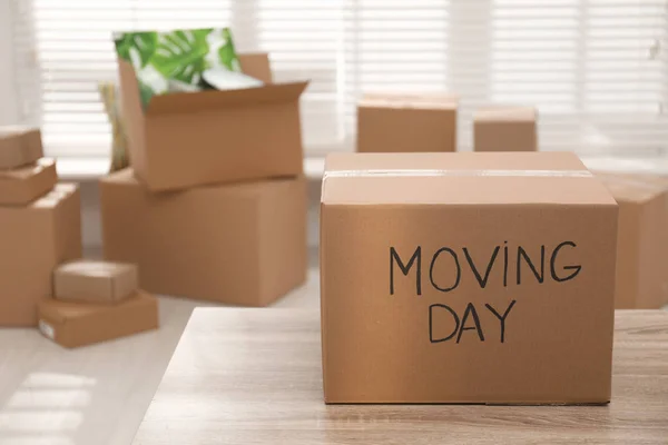 Scatola di cartone con parole MOVING DAY sul tavolo di legno — Foto Stock