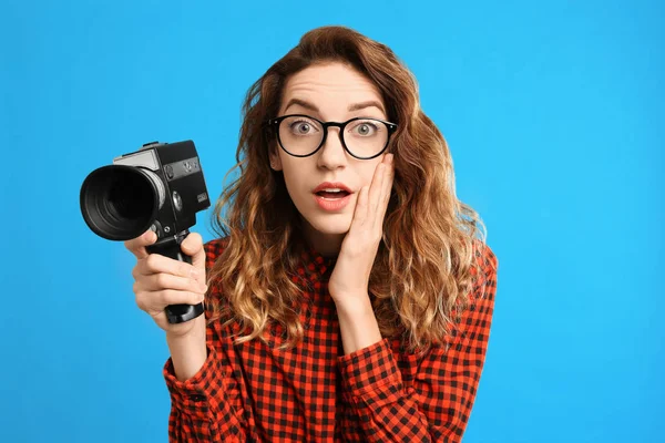 Mooie jonge vrouw met vintage video camera op licht blauw ba — Stockfoto