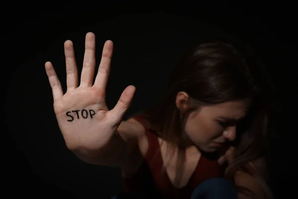Piangendo giovane donna mostrando palmo con la parola STOP contro bac nero — Foto Stock