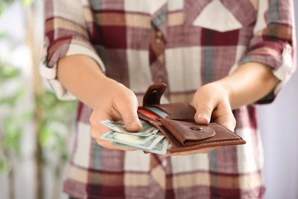 Женщина кладет деньги в бумажник на размытом фоне, крупным планом — стоковое фото