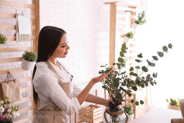 Floristería con ramas verdes a la mesa en taller — Foto de Stock