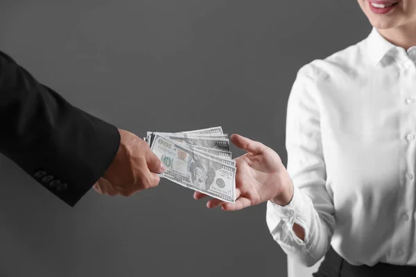 Man giving bribe money to woman on dark background, closeup