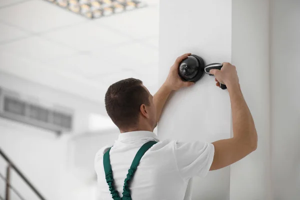 Técnico instalando câmera CCTV na parede dentro de casa — Fotografia de Stock