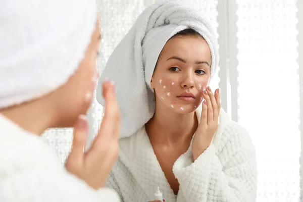 Menina adolescente com problema de acne aplicando creme perto do espelho na bathro — Fotografia de Stock