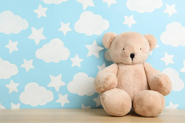 Teddybär auf Holztisch neben Wand mit gemaltem blauem Himmel, spac — Stockfoto