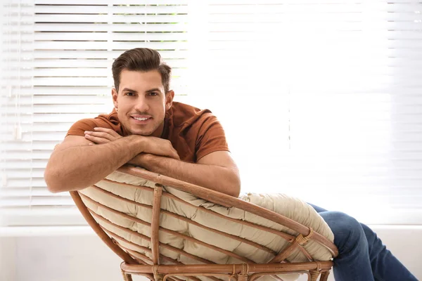 Homme attrayant relaxant dans une chaise papasan près de la fenêtre à la maison — Photo