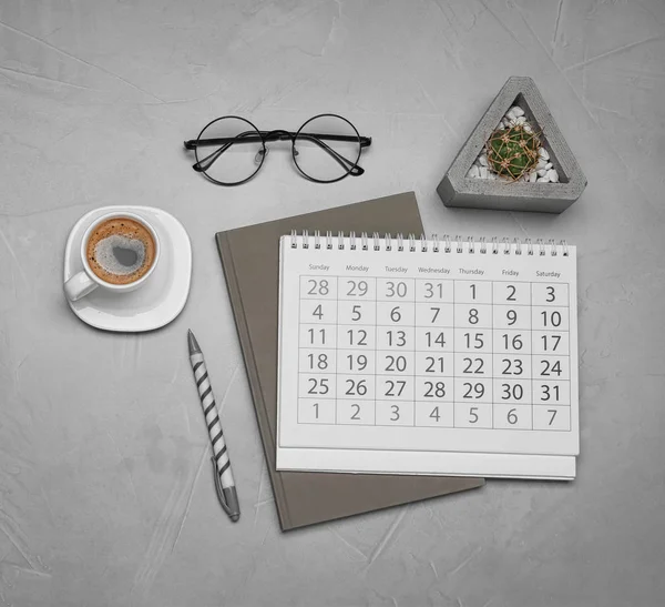 Platt låg sammansättning med kalender och kopp kaffe på grå flik — Stockfoto