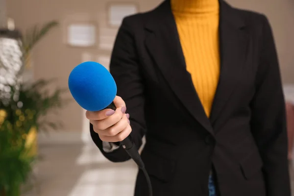Professional journalist with modern microphone in room, closeup