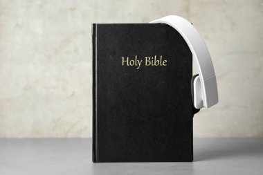 Masada açık gri arka plana karşı İncil ve kulaklıklar. Dini sesli kitap