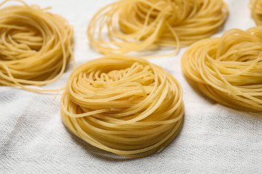 Beyaz masa örtüsü üzerinde Capellini makarnası, yakın çekim görünümü