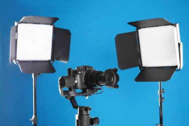 Mavi arka planda profesyonel video kamera ve ışıklandırma ekipmanları