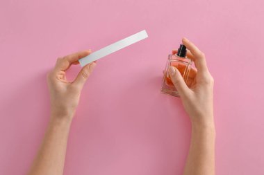 Pembe arka planda parfüm şişesi ve reklamı olan bir kadın.