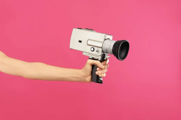 Vrouw met vintage video camera op karmozijnrode achtergrond, close-up o — Stockfoto