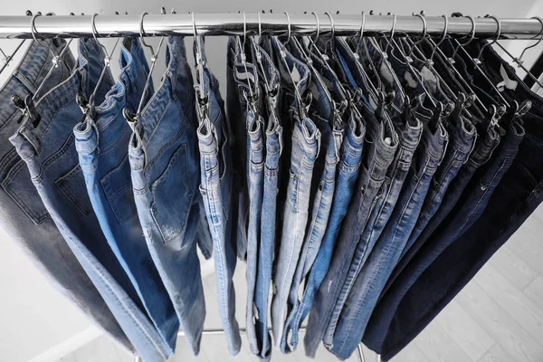 Cremalheira com jeans diferentes perto de fundo claro, close-up — Fotografia de Stock