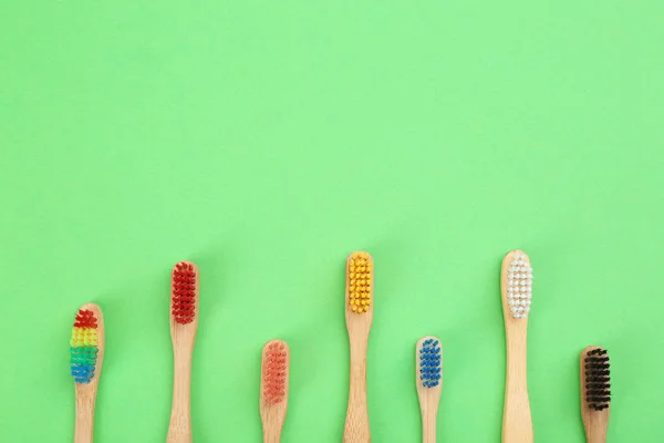 Natural toothbrushes made with bamboo on green background, flat — Stock Photo, Image