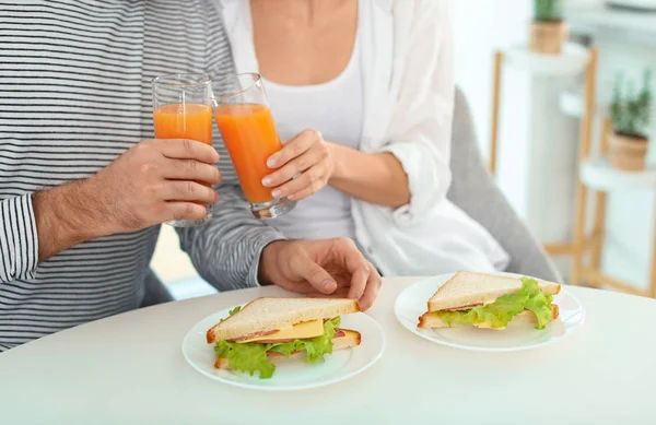 Pareja joven desayunando con sándwiches en la mesa en kitche — Foto de Stock