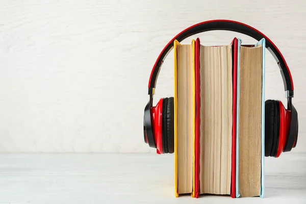 Książki i nowoczesne słuchawki na białym drewnianym stole. Przestrzeń dla tex — Zdjęcie stockowe