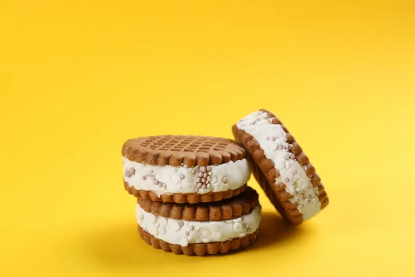 Sweet delicious ice cream cookie sandwiches on yellow background