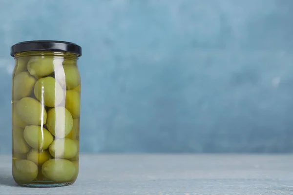 Tarro de vidrio con aceitunas en escabeche en la mesa. Espacio para texto — Foto de Stock