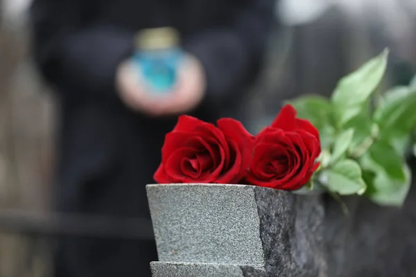 Czerwone róże na szarym granitowym nagrobku na zewnątrz. Ceremonia pogrzebu — Zdjęcie stockowe